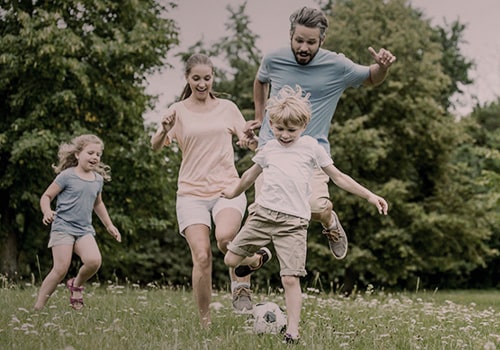 Семья с двумя детьми играют в футбол